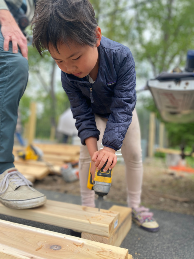 1st grader using power tool to build raised bed